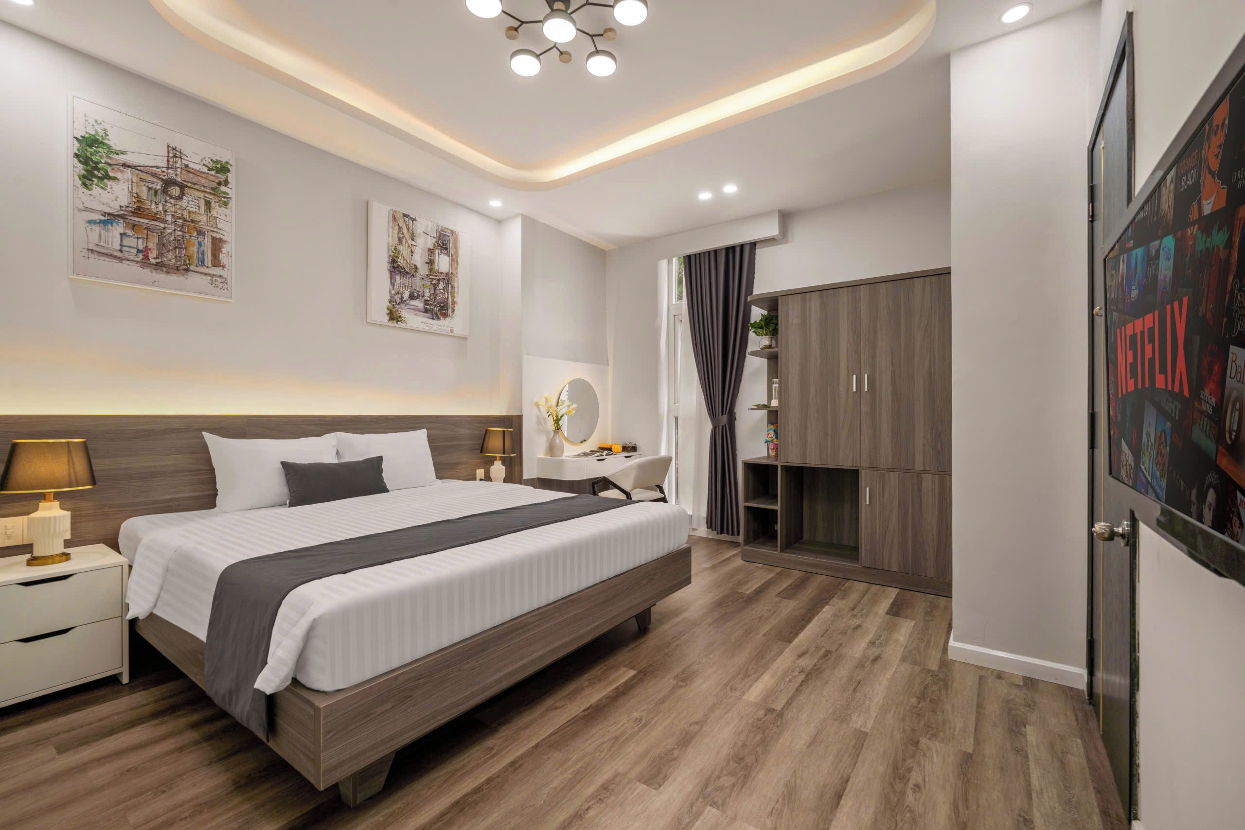 A modern bedroom with a large bed, bedside tables, a wardrobe, and a wall-mounted TV.