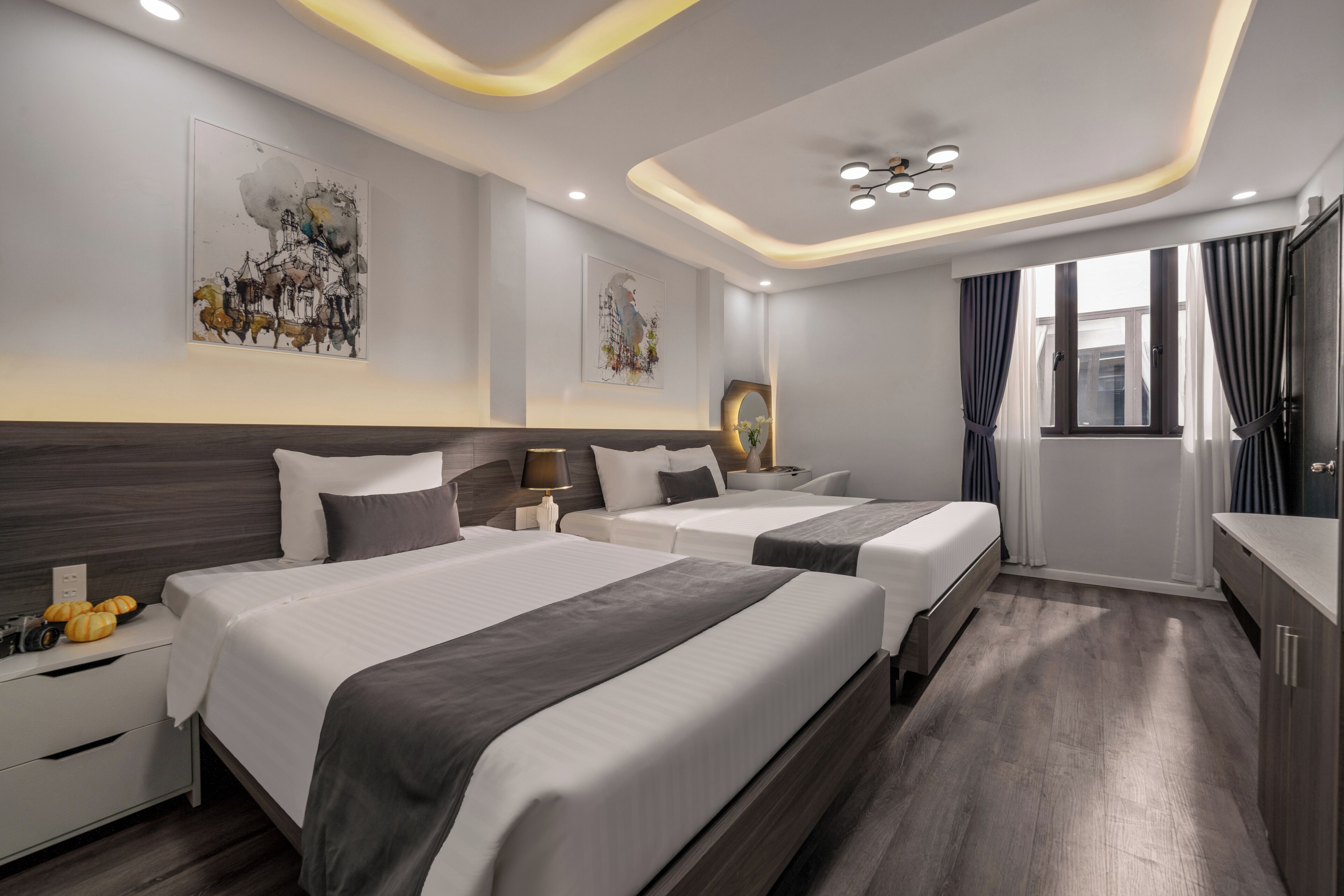 Ein modernes Hotelzimmer mit zwei Betten, einem Nachttisch, einem Spiegel und Kunstwerken an den Wänden.