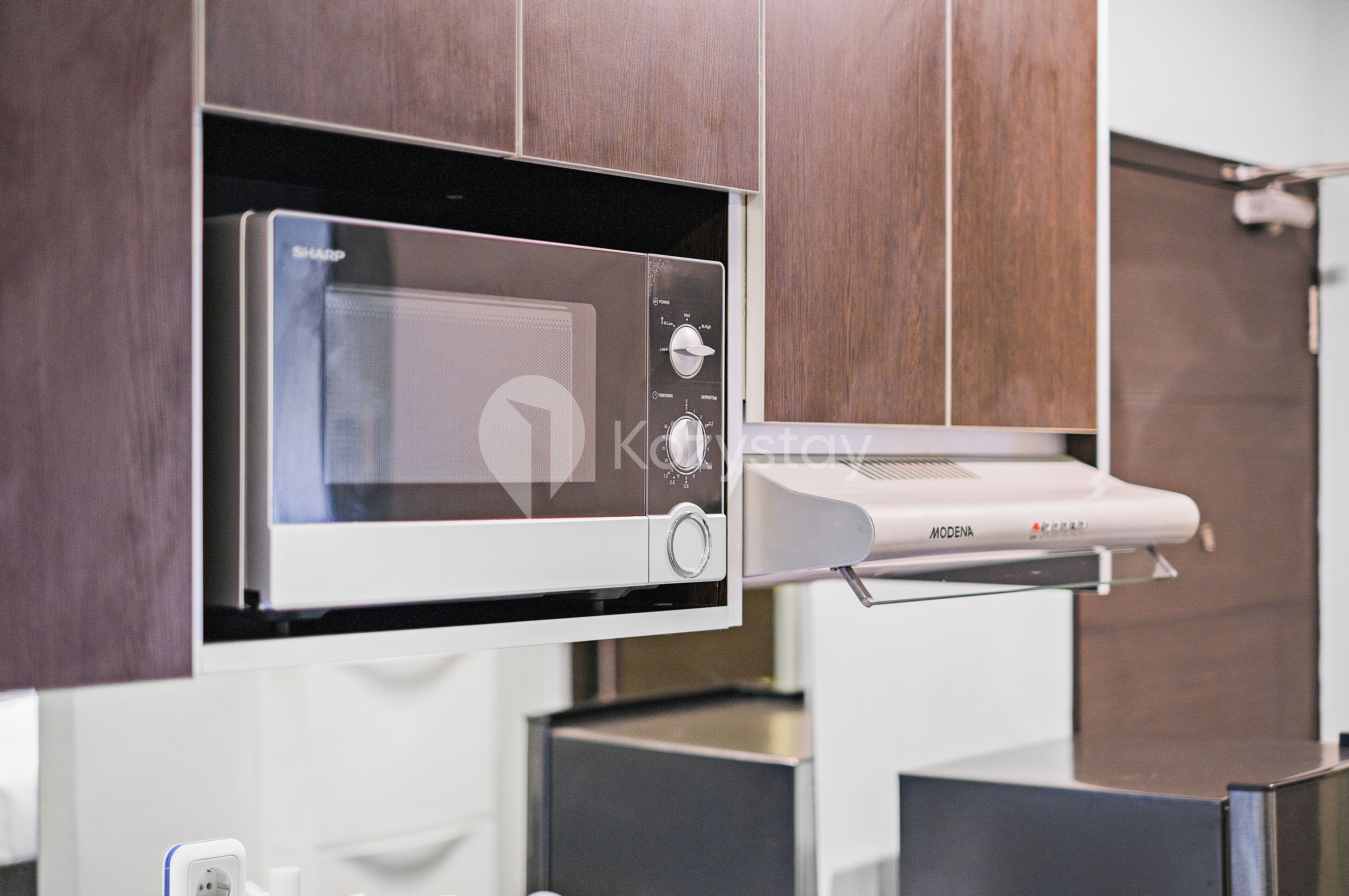 A modern kitchen with a built-in microwave and a range hood.