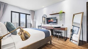 A modern bedroom with a bed, desk, chair, and a large mirror.