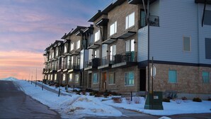A row of modern multi-story residential buildings with balconies, a snow-covered ground, and a clear sky. - Luxury Townhome (Park City)