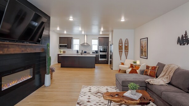 A modern living room with a fireplace, a large TV, and a cozy seating area. - Luxury Townhome (Park City)