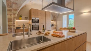 Una cucina moderna con una grande isola, elettrodomestici in acciaio inossidabile e vista sull'esterno.