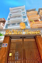 Entrada de un hotel con un cartel que dice "De Mei House" y un logotipo encima.