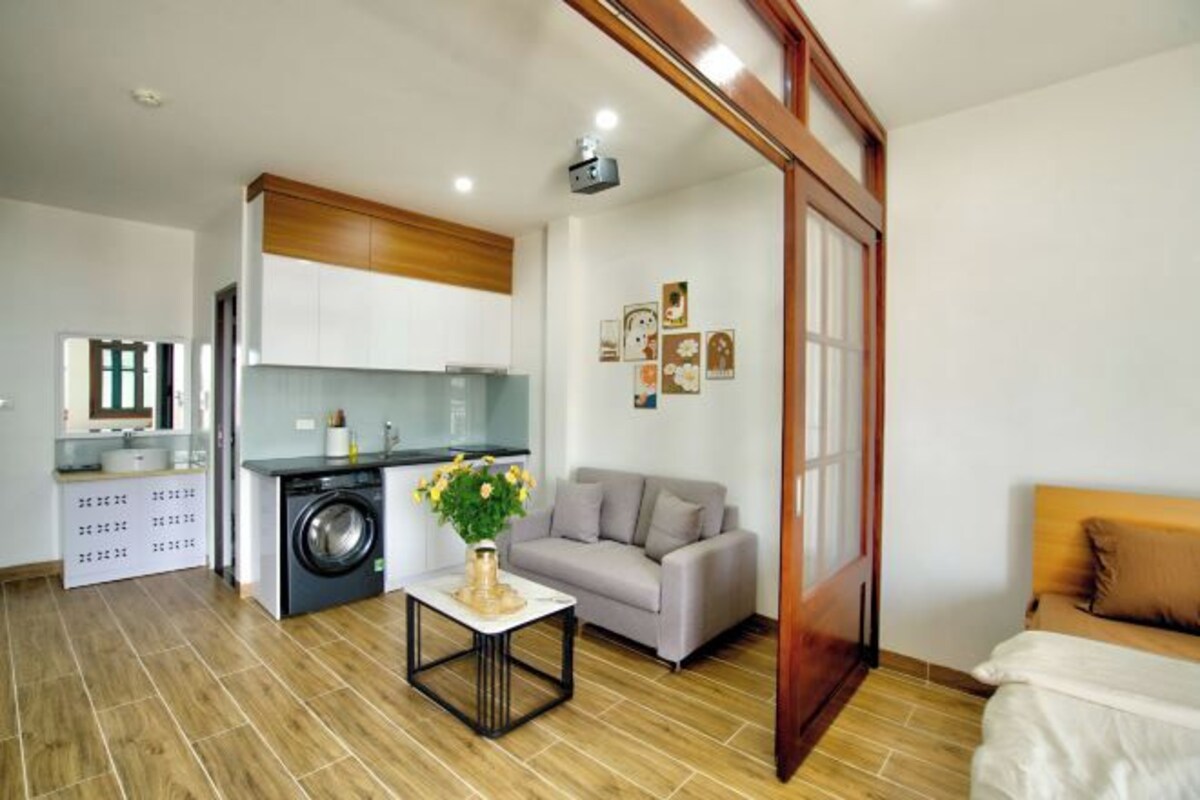 A compact living space with a kitchenette, a sofa, a dining table, and a bed.