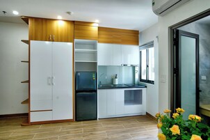 Una cocina moderna con armarios blancos, un refrigerador negro y paneles de madera en los gabinetes superiores.