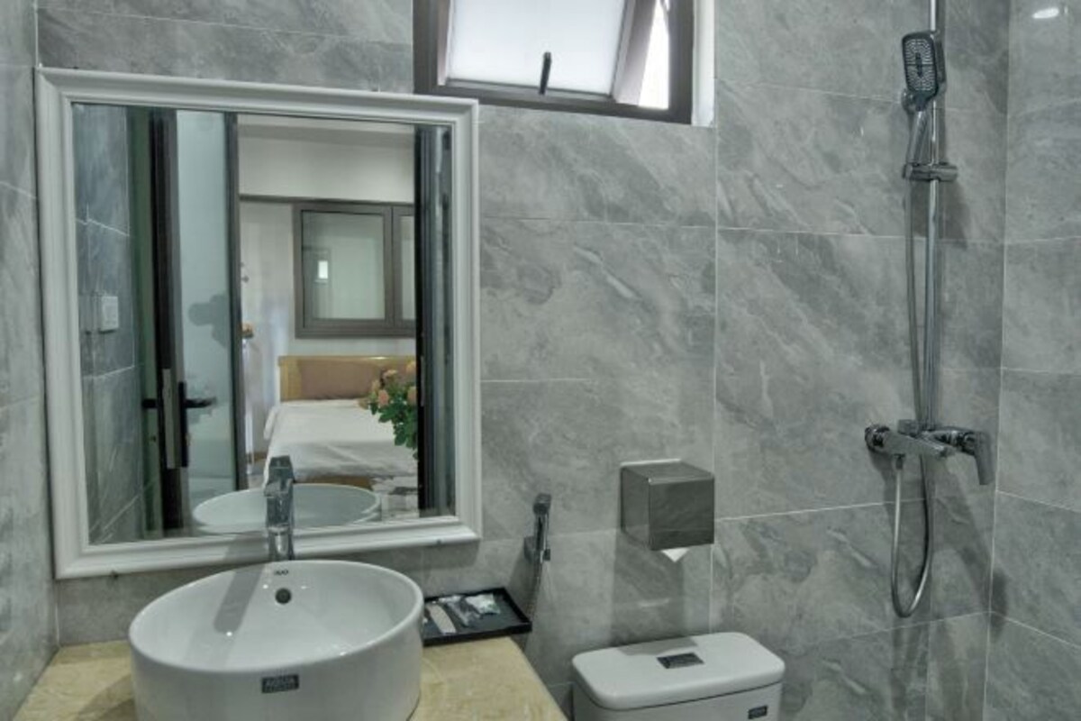 A modern bathroom with a large mirror, a sink, a toilet, and a shower.