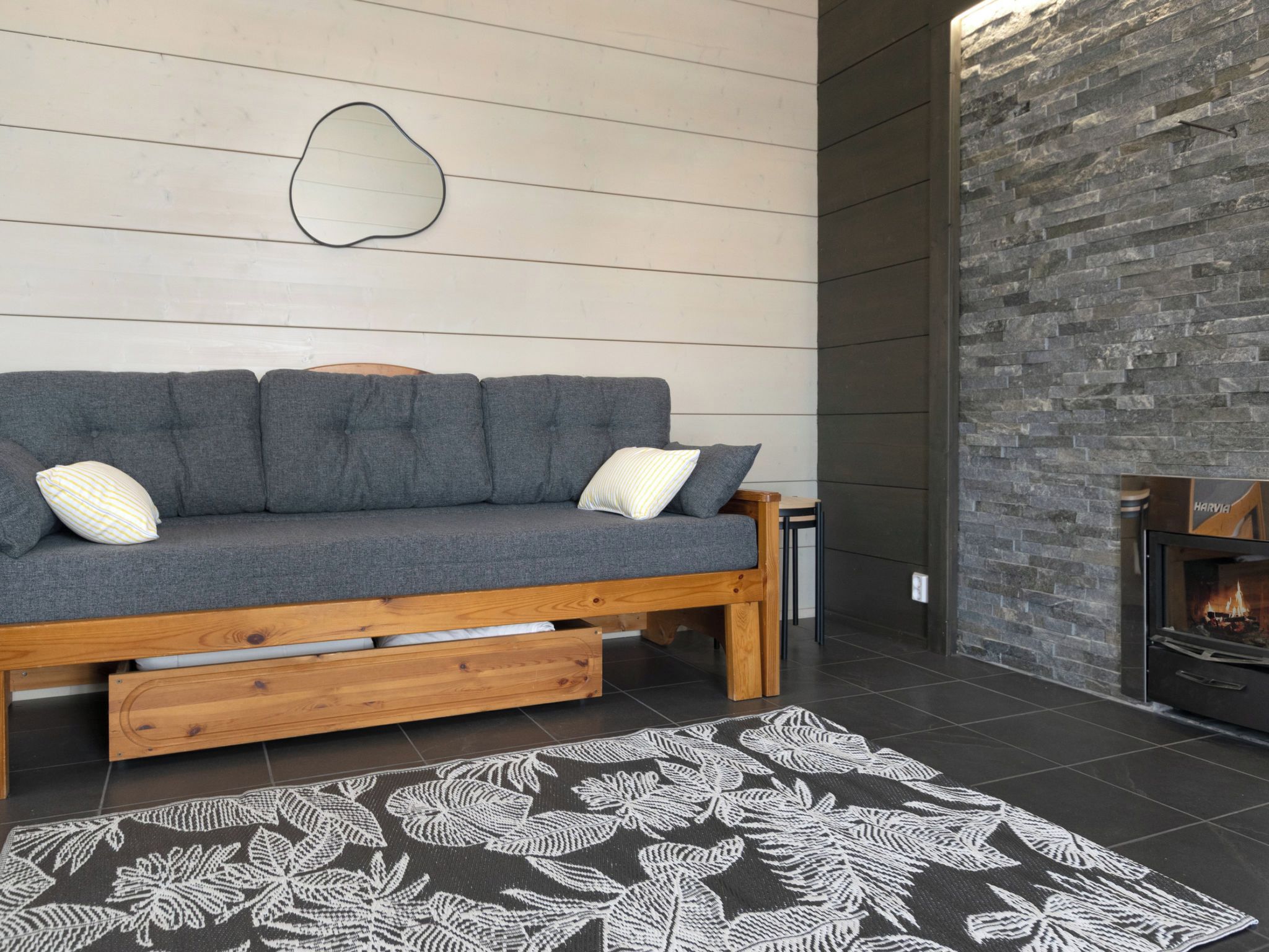A cozy living room with a grey sofa, wooden side table, and a fireplace.