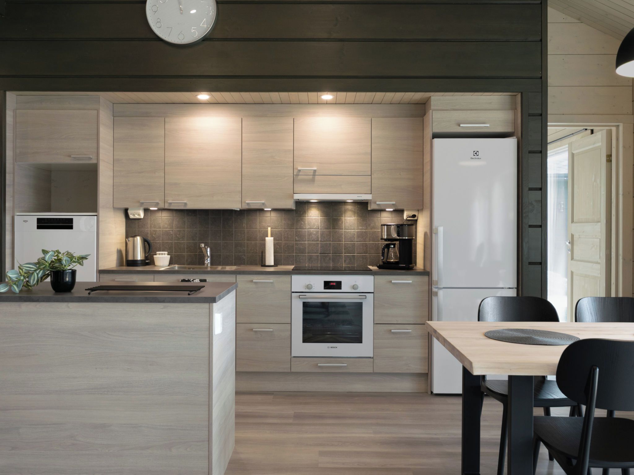 Eine moderne Küche mit einer zentralen Kochinsel, integriertem Backofen und einem Kühlschrank.