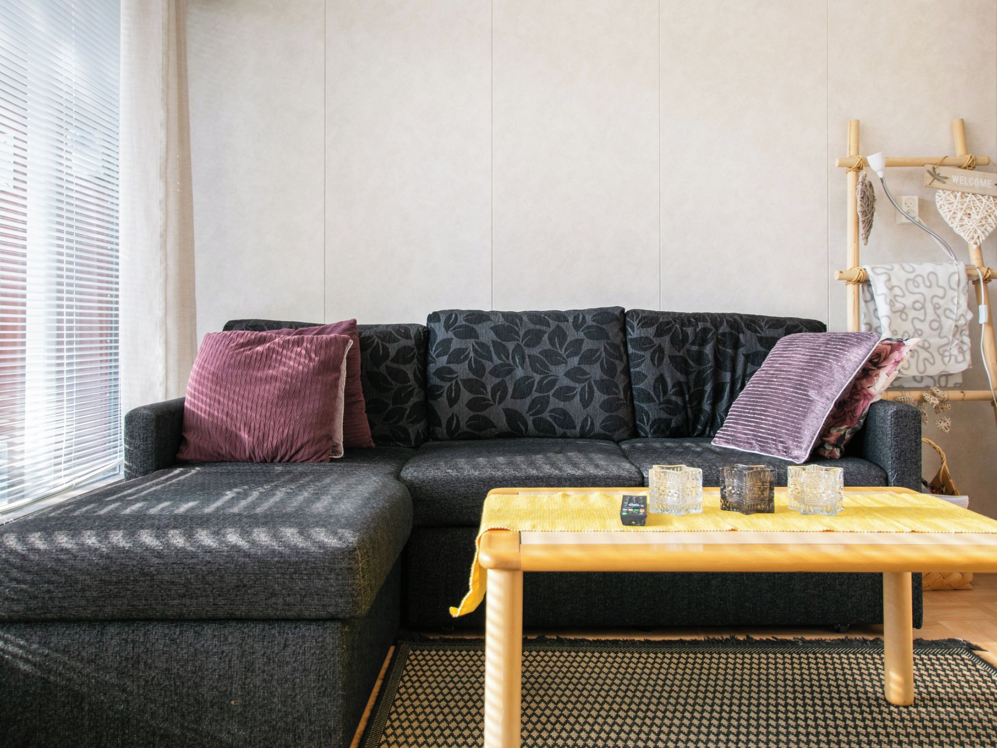 A living room with a sofa, cushions, a coffee table, and a wall-mounted decoration.