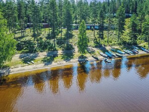 Vue aérienne d’une propriété au bord du lac, avec un quai, des bateaux et une zone boisée.