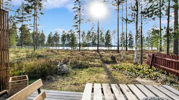 Puinen terassi, jossa on penkki ja pöytä, ja josta avautuu näkymä metsään ja vesistöön.