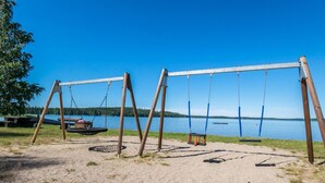 Une balançoire installée au bord d’un lac, offrant une vue dégagée sur l’eau et les arbres en arrière-plan.