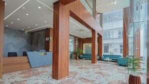 Uma área de recepção moderna com piso de mármore, balcão de madeira e espaço de estar com sofás.