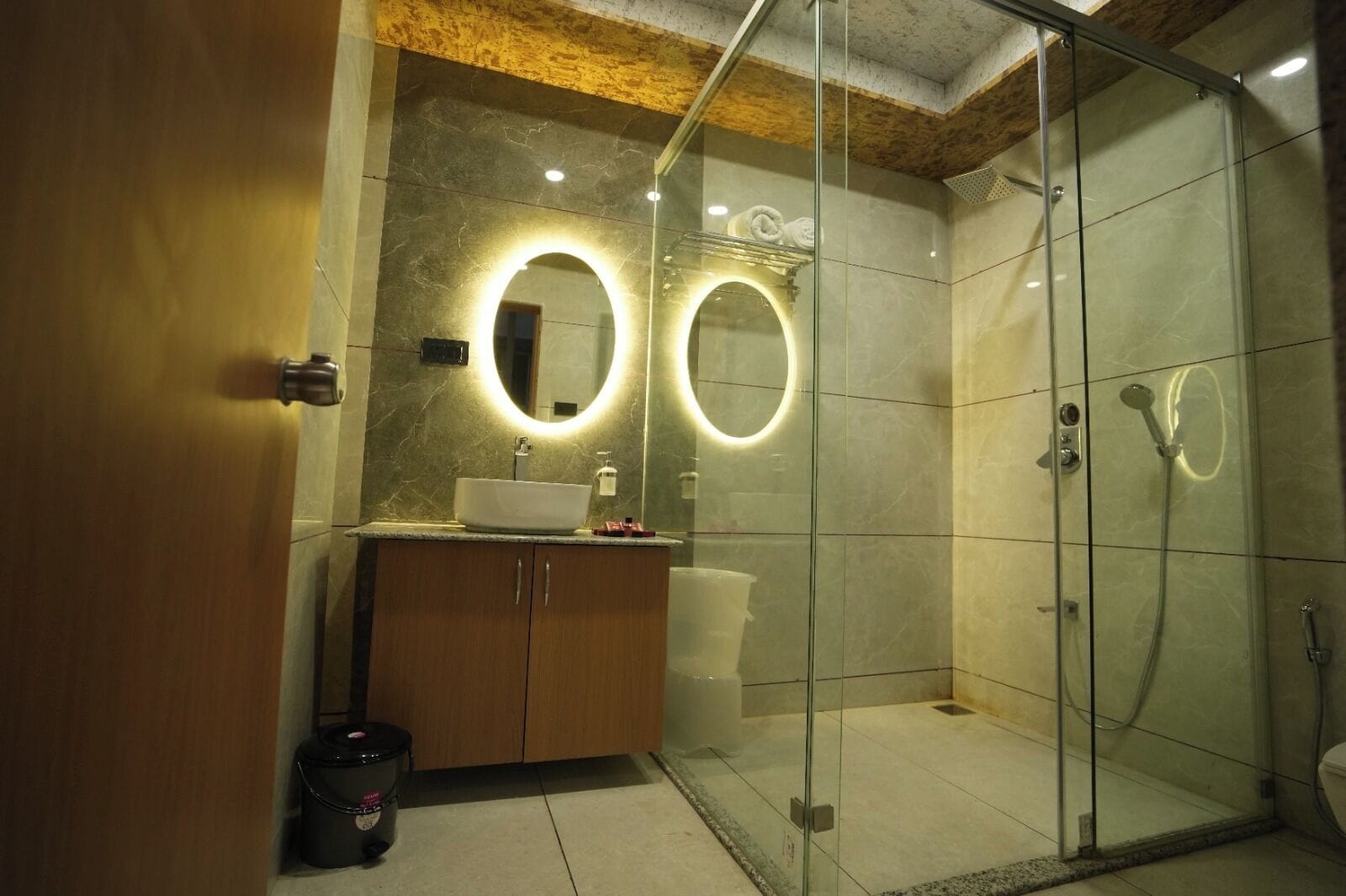 A modern bathroom with a glass-enclosed shower, a vanity with a sink and mirror, and a wooden cabinet.