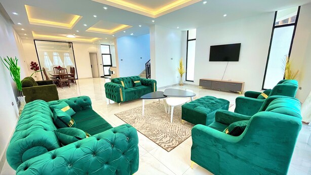 Una sala de estar moderna con sofás tapizados en verde, una mesa de centro y un televisor de pantalla plana montado en la pared.