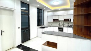 Una cocina moderna con armarios blancos, horno empotrado y estante de madera.