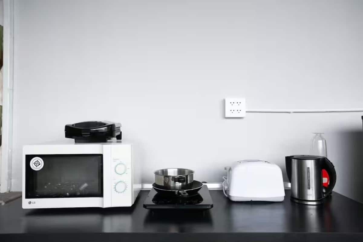 A kitchen with a microwave, toaster, kettle, and a small induction cooktop.