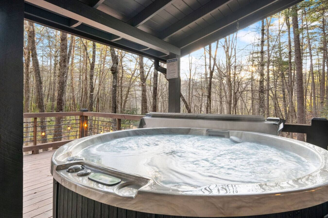 Un jacuzzi en una terraza de madera con vista al bosque.