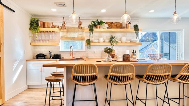 A kitchen with a central island, bar stools, pendant lights, and shelves with plants. - A Mythia World: Garden Oasis l Private Resort (Tobyhanna)