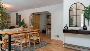 A modern kitchen with a wooden table and chairs, a zebra-patterned rug, and a large mirror above the counter. - A Mythia World: Garden Oasis l Private Resort (Tobyhanna)