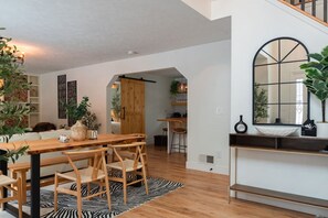 Una cucina moderna con un tavolo e sedie in legno, un tappeto a motivi zebrati e un grande specchio sopra il bancone.