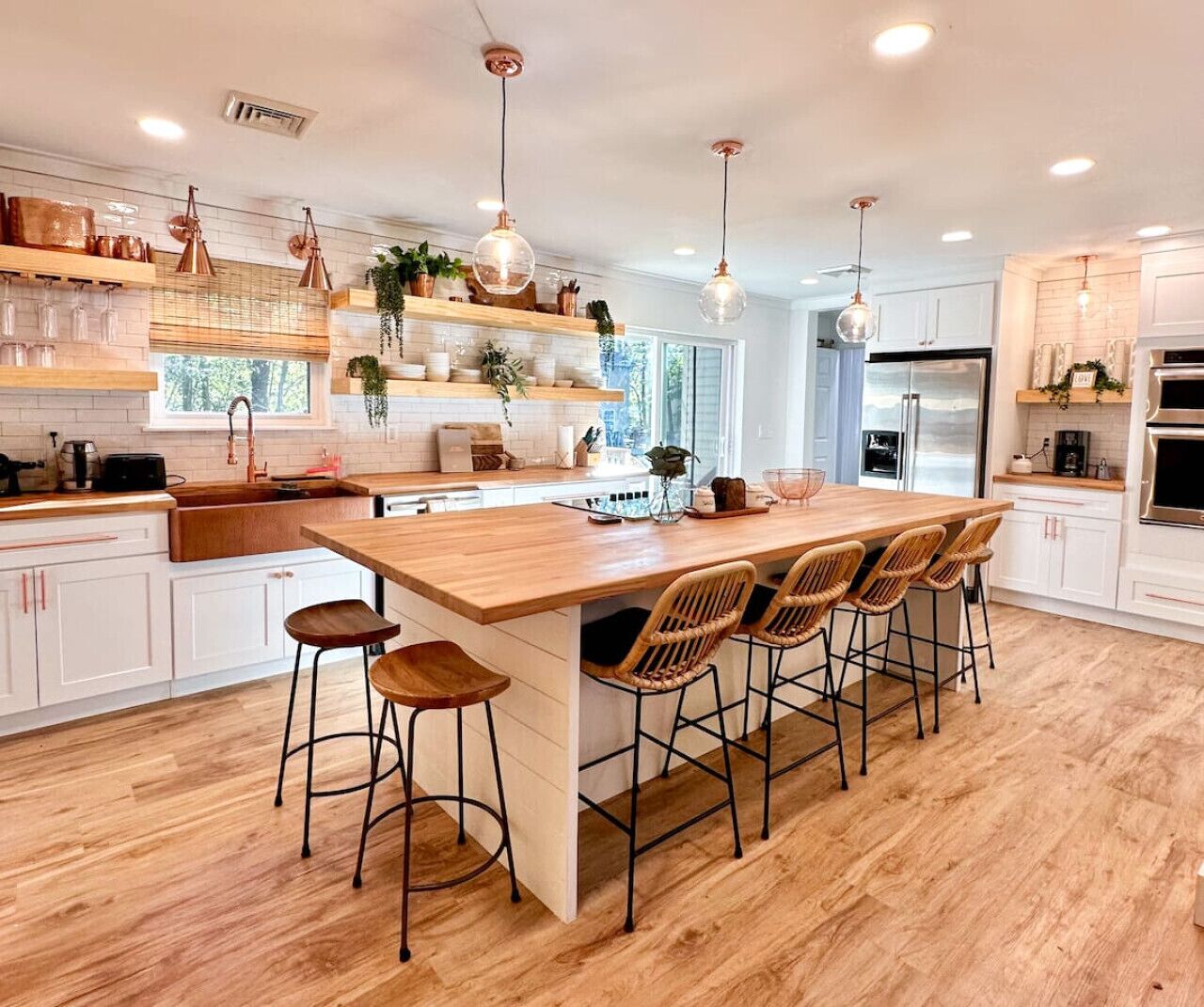 A modern kitchen with a central island, bar stools, pendant lighting, and white cabinetry.