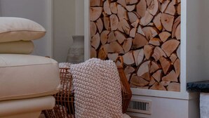 A living room with a sofa, a knitted throw, a basket, and a bookshelf with books and a white vase. - A Mythia World: Garden Oasis l Private Resort (Tobyhanna)