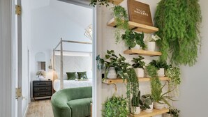 A modern bedroom with a green sofa, a bed, a bedside table, and a wall-mounted plant shelf. - A Mythia World: Garden Oasis l Private Resort (Tobyhanna)