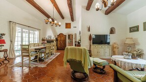 A spacious living room with a dining area, a television, and a statue. - Villa Hokiss - Private pool on 1 ha of nature (Le Muy)