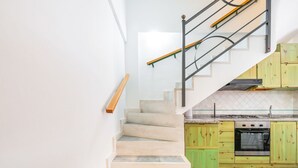 A staircase with beige steps leading to a kitchen area with green cabinets and a black stove.