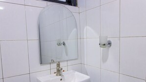 Un bany amb un lavabo blanc, un mirall i un dosificador de sabó.