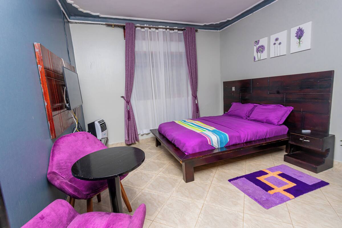 A bedroom with a bed, a desk, a chair, and a window with curtains.