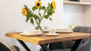 A dining table with a vase of sunflowers, white plates, a white cup, and a green glass.