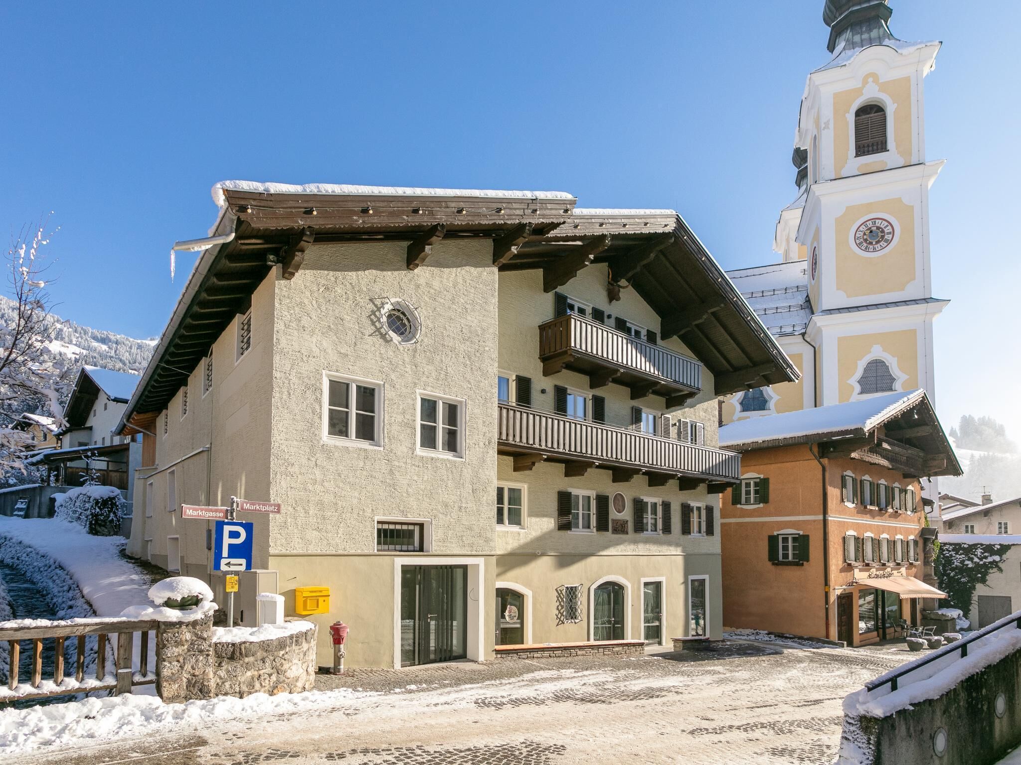 A traditional building with a balcony, a clock tower, and a cobblestone street.