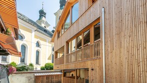 A modern wooden building with balconies and large windows.