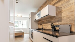 A modern kitchen with white cabinetry, a wooden accent wall, and a built-in microwave.