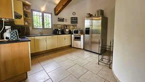 Une cuisine avec des meubles en bois, un réfrigérateur en acier inoxydable, un four à micro-ondes et une machine à café.