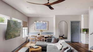 A modern living room with a gray sectional sofa, a wooden coffee table, and a ceiling fan. - Rare 5BR East Austin Home | Shared Pool & DT Drive (Austin)