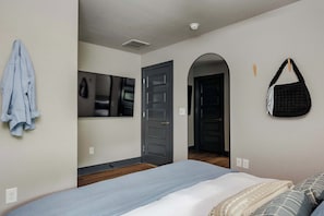 Un dormitorio con cama, espejo, puerta y bolso colgado.