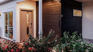 A modern building with a glass door entrance, a dark exterior wall, and a small window. - Rare 5BR East Austin Home | Shared Pool & DT Drive (Austin)