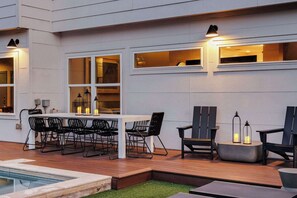 Un patio exterior con piscina, una mesa de comedor con sillas y una zona de bar con mostrador.