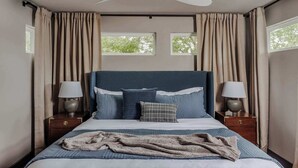 A bedroom with a bed, two bedside tables with lamps, a ceiling fan, and two windows with curtains. - Rare 5BR East Austin Home | Shared Pool & DT Drive (Austin)