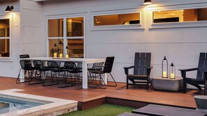 An outdoor patio with a pool, a dining table with chairs, and a seating area with lamps. - Rare 5BR East Austin Home | Shared Pool & DT Drive (Austin)