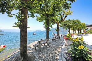 A lakeside promenade with benches, potted plants, and a view of boats on the water. - Il Porticciolo - Lake Front Panoramic Apartment (Castelveccana)