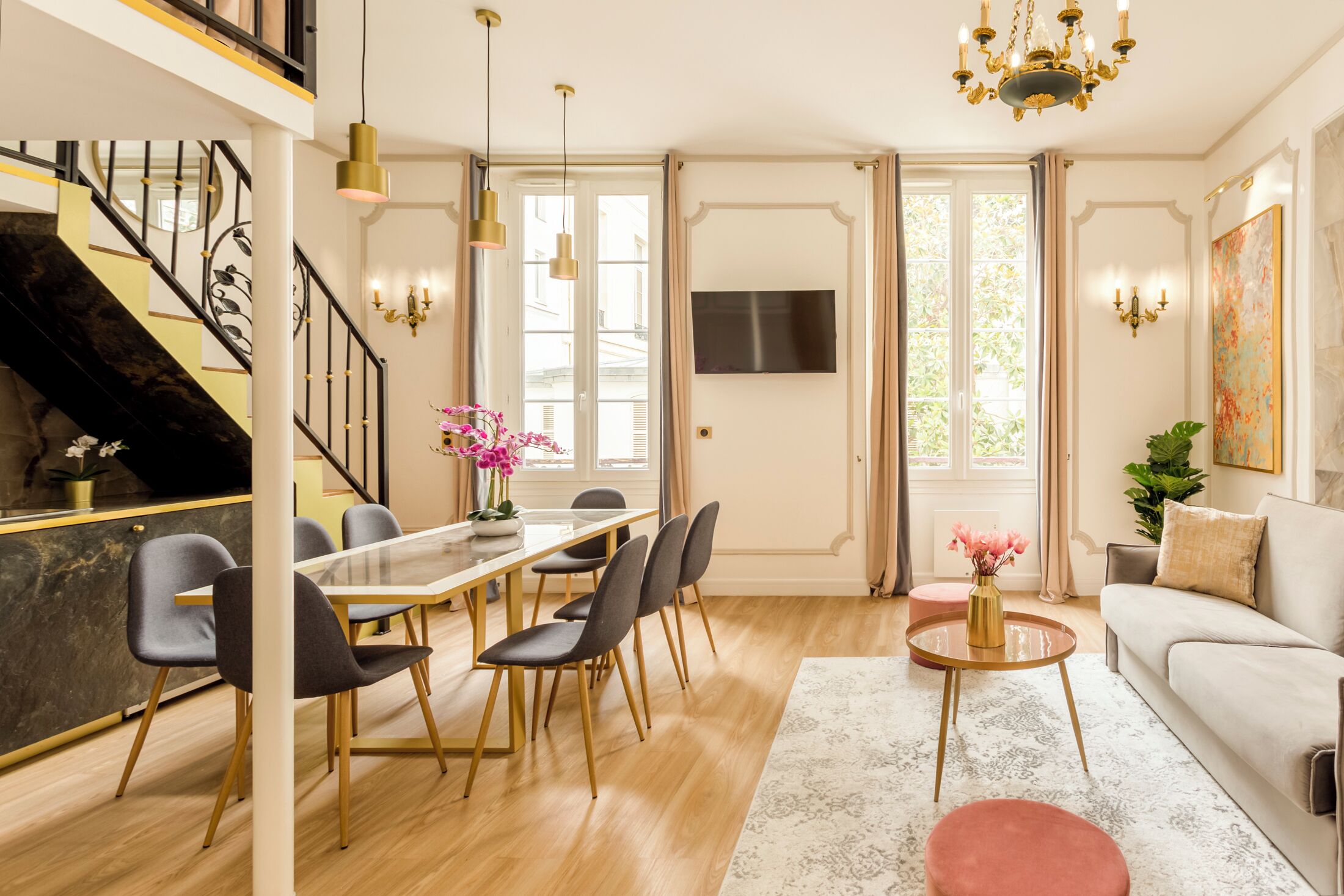 Ein modernes Wohnzimmer mit Essbereich, Treppe und großem Fenster.