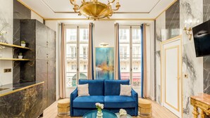 Un salon luxueux avec un canapé bleu, une table basse en verre et un grand tableau abstrait.