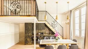 Une cuisine moderne avec des plans de travail sombres et un coin repas comprenant une table en marbre et des chaises grises.