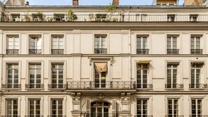 Un immeuble à plusieurs étages de style architectural classique, caractérisé par des fenêtres disposées de manière symétrique et des balcons richement décorés.