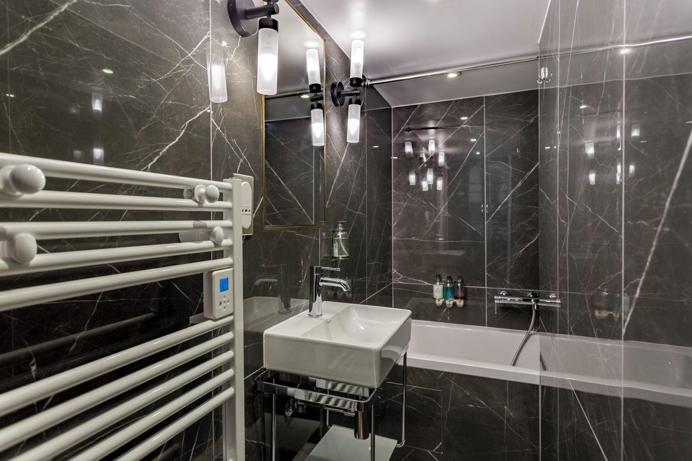 Une salle de bain moderne avec un lavabo blanc, une baignoire et une cabine de douche en verre.